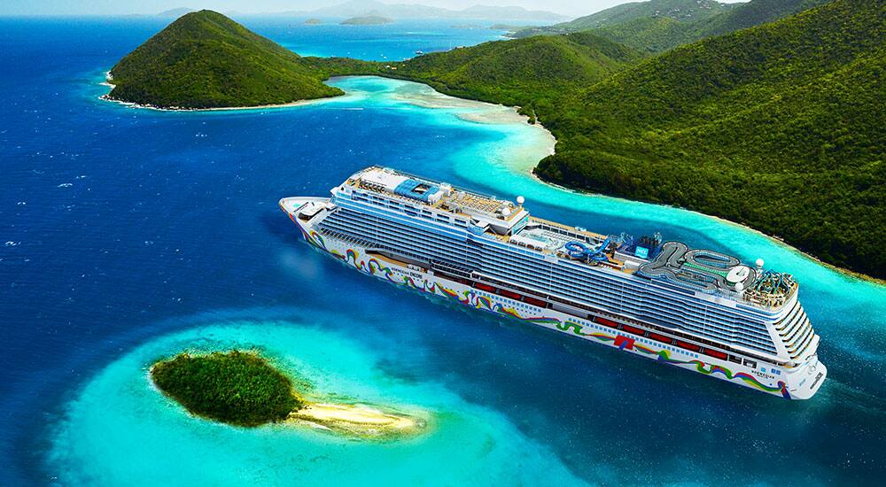 Cruise ship sailing through turquoise waters beside tropical islands