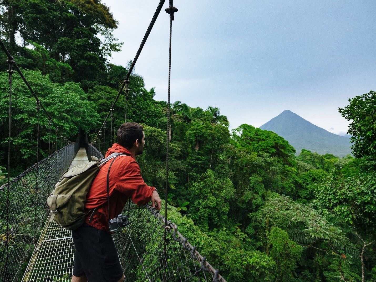 Rainforest suspension bridge with Arenal Volcano in the distance