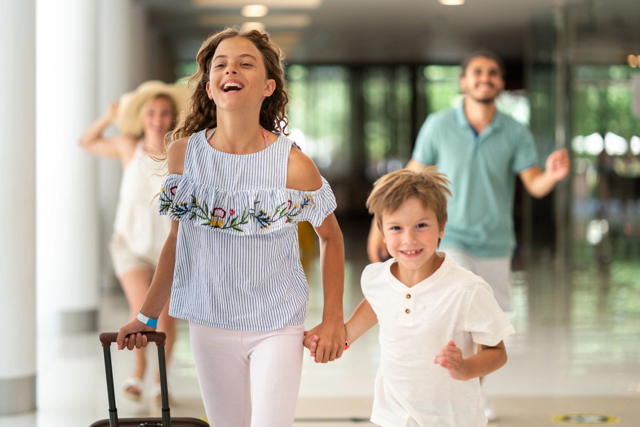Kids running with luggage in a hotel lobby